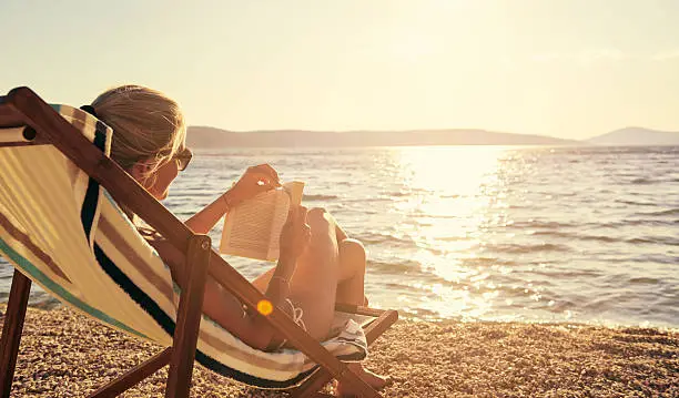 A young woman reading a book while sitting on a chair at the beachhttp://195.154.178.81/DATA/i_collage/pu/shoots/805670.jpg