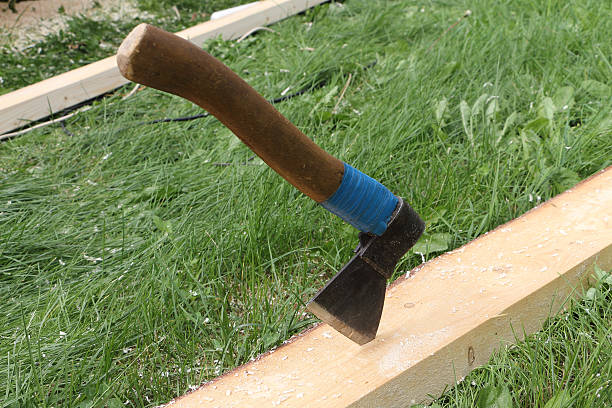 istock Axe in a pine board against a grass outdoors 491408036