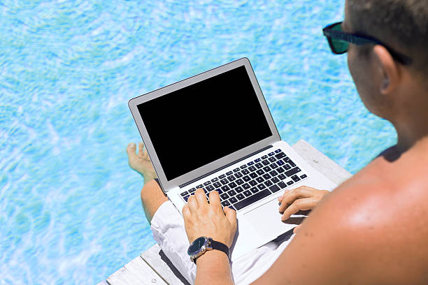 istock Man working with laptop computer by the swimming pool 491410440