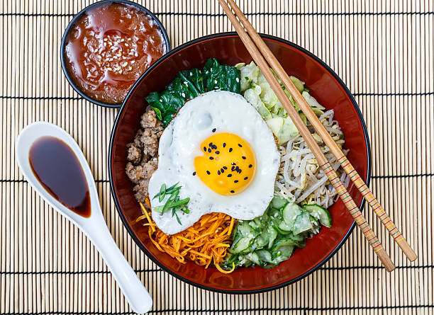 bibimbap in a bowl with sauces on bamboo mat, korean