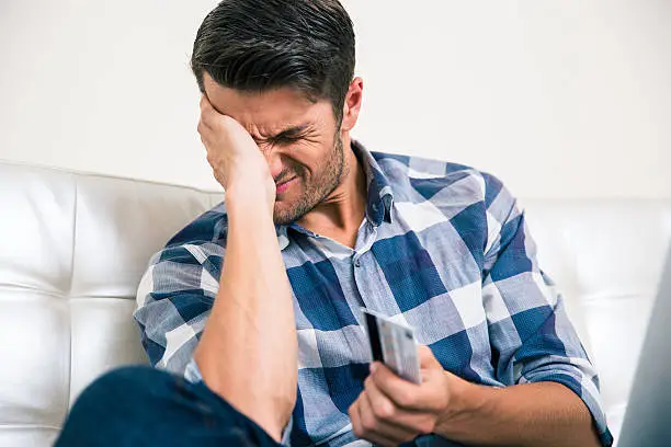 Photo of Sad man holding bank card