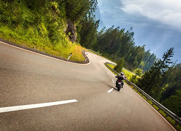 Biker in Austrian mountains riding on curve road, Alps, Europe, speed and freedom concept, luxury transport, active travel and tourism