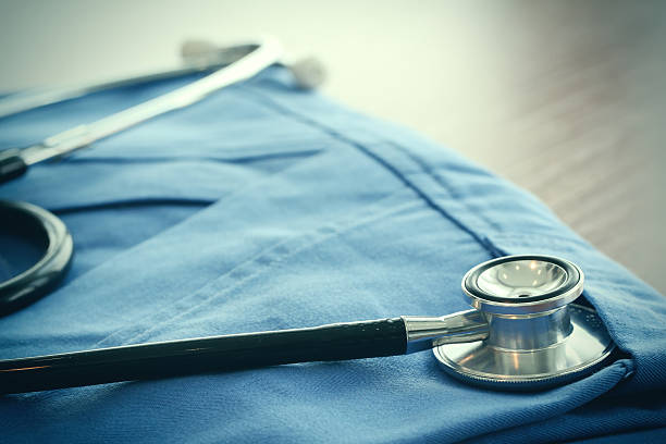 istock Stethoscope with blue doctor coat on wooden table 491427284