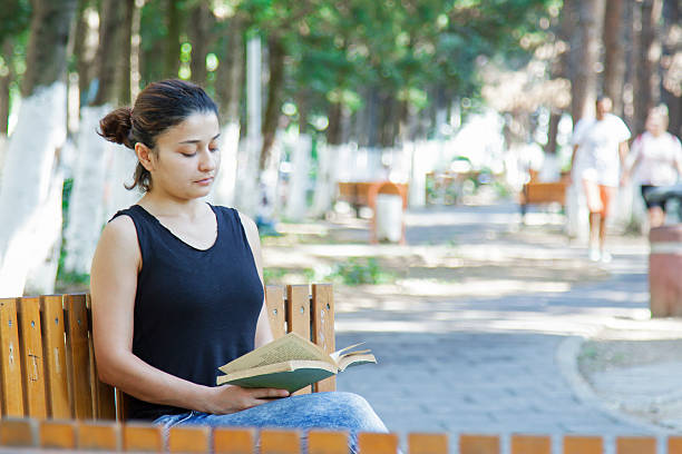 istock Woman reading book in park 491430810