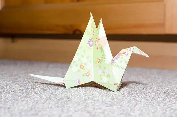 A paper folding, origami of a bird closeup on a grey carpetOne paper folding, origami of a bird closeup on a grey carpet