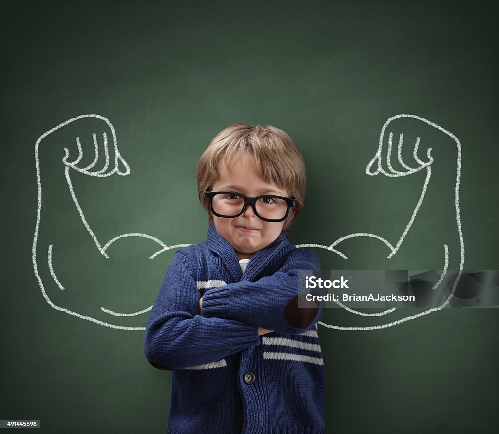 Strong man child showing bicep muscles Strong man child showing bicep muscles concept for strength, confidence or defence from bullying Child Stock Photo