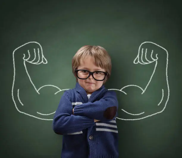 Strong man child showing bicep muscles concept for strength, confidence or defence from bullying