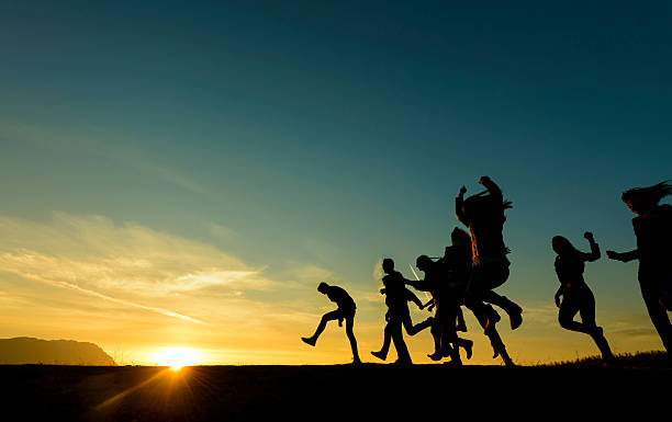 happy friends silhouettes running and having energy, sunset time.