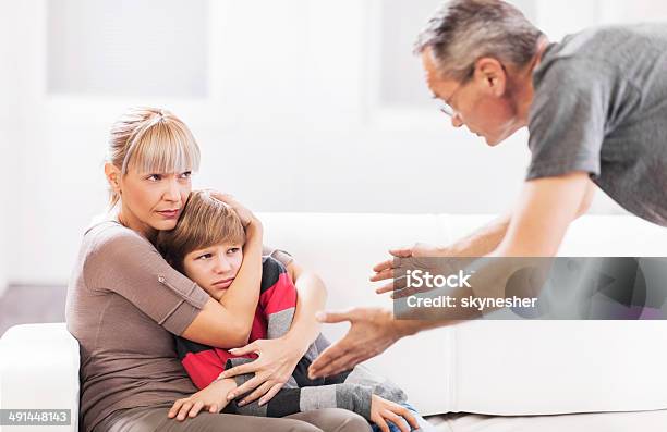 Mother Defending Her Son While Father Is Scolding Him Stock Photo - Download Image Now