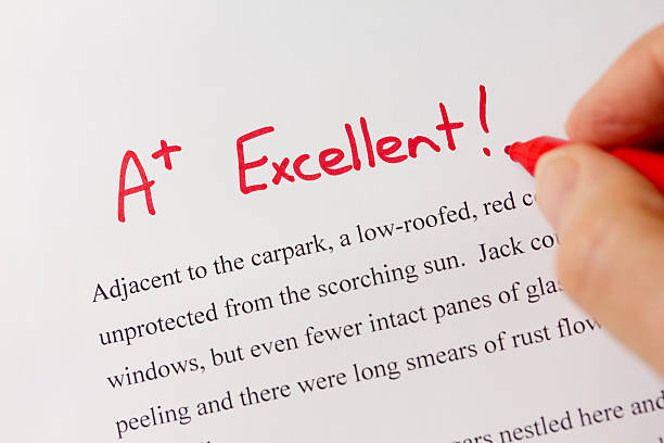 Hand and Red Pen Grading Successful Essay with Excellent stock photo