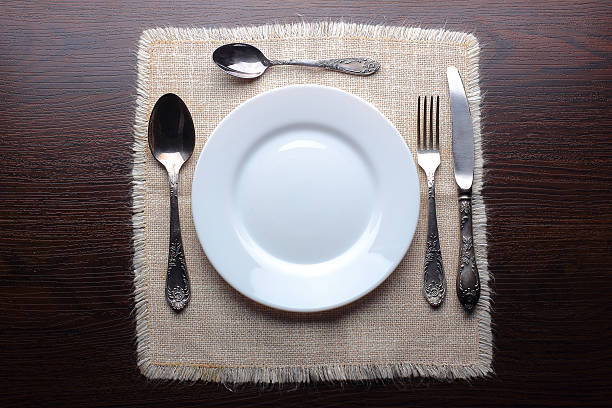 istock White plate, knife, fork and spoons on wooden background 491451132