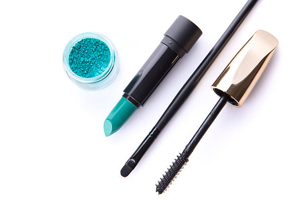 Top view of loose eye shadow, lipstick, makeup brush, and mascara, isolated on white background