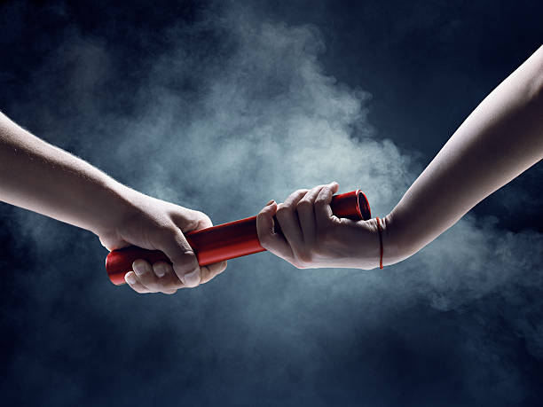 Close up of exchanging relay baton on a race Close up of exchanging relay baton on a race on a black background with smoke relay photos stock pictures, royalty-free photos & images