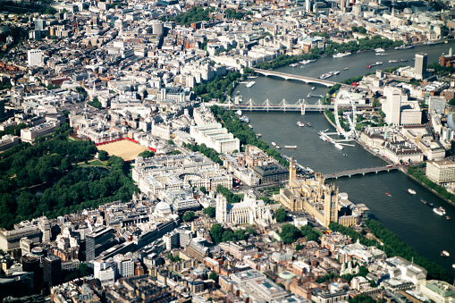 An aerial view of London following the River thames; Waterloo, Hungerford and Westminster Bridges. The Houses of Parliament and the London Eye are visible central right. Taken from within an aeroplane. Daylight, nobody, horizontal composition. 