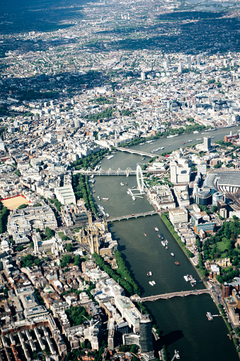 An aerial view of London following the River thames; from Waterloo Bridge to Lambeth Bridge. Westminster Bridge, the Houses of Parliament and the London Eye are visible centrally. Taken from within an aeroplane. Daylight, nobody, vertical composition. 