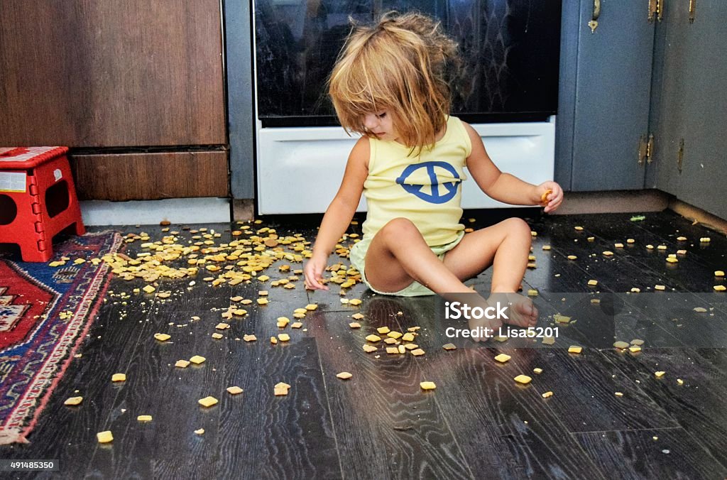Terrible two's Little girl spills a snack all over the floor, but seems content to eat it anyway Child Stock Photo