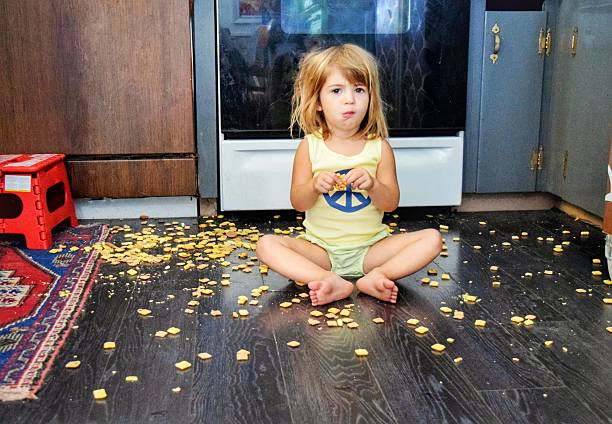 What!? I got my own snack Toddler spills a snack all over the floor, but seems content to eat it anyways breakfast cereal photos stock pictures, royalty-free photos & images