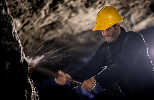 Latin American miner working at the mine digging with a pick - mining concepts