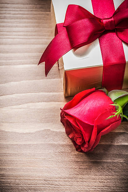 istock Boxed present with tied bow expanded rose on wooden board 491498554