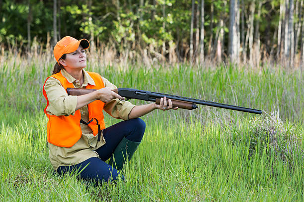 istock Female hunter with shotgun kneeling in tall grass 491511802