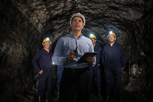 Engineer leading a group of miners Engineer leading a group of miners working at the mine underground using a tablet computer - mining concepts lead mine stock pictures, royalty-free photos & images