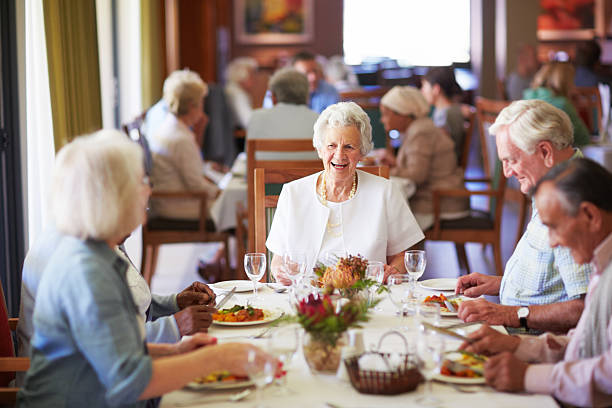 Reminiscing with friends at the dining table A group of elderly people having lunch together at a nursing home retirement community stock pictures, royalty-free photos & images