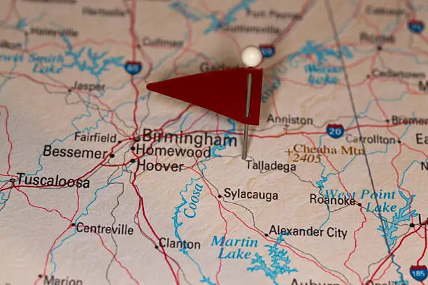 A map pin with a red flag pinpoints the city on a select area from a high quality map.  The red flag creates highlighted copy space for text.