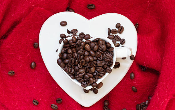 istock Heart shaped cup with coffee beans on red 491529754