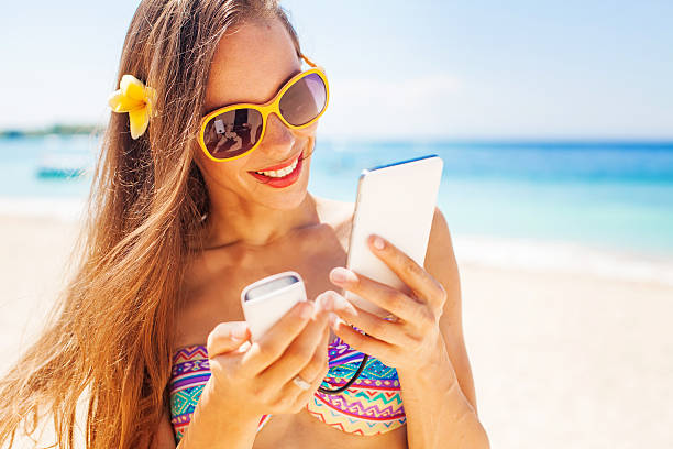 istock woman on a beach holding a phone in her hands 491531286