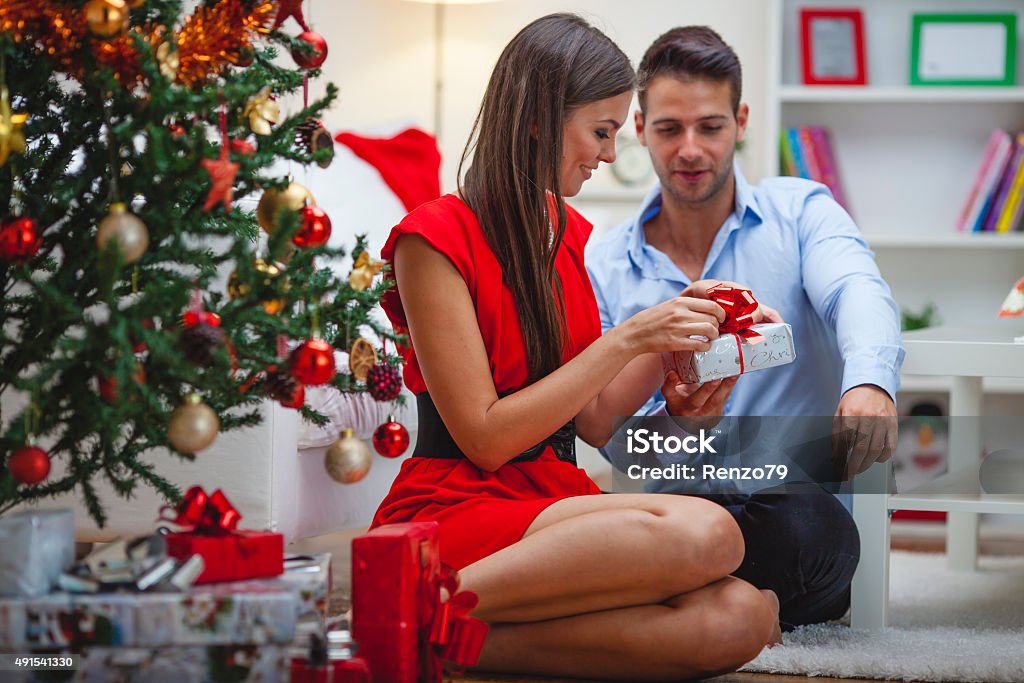 Engagement at Christmas Time Happy Young couple sitting on sofa at christmas evening Christmas Stock Photo