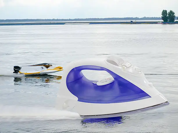 Modern electric steam iron against the background of the racing of Formula-1 on the water