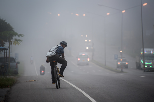 Krabi , Thailand - October 7, 2015: Man ride to work  in poor visibility road effect from Haze caused by forest fires in Indonesia