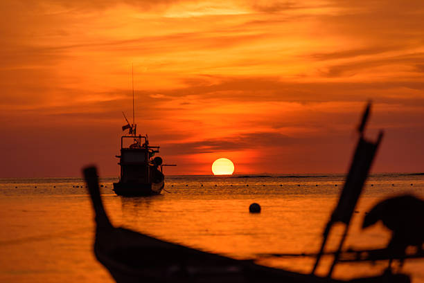 istock silhouette fishing boat at sunset 491558352