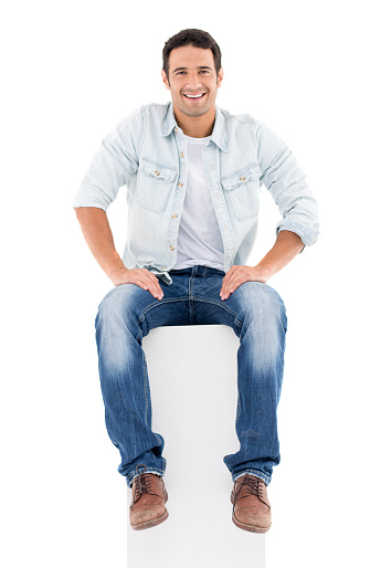 Fullbody casual man sitting in a tall column and looking happy - isolated over white background