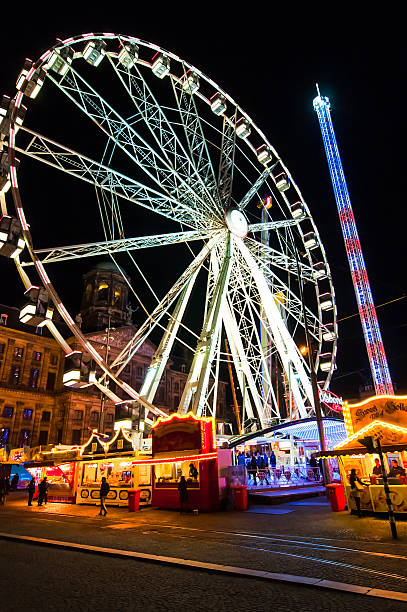 ferris wheel 夜にダム広場に出ます。王の日、アムステルダムます。 - editorial outdoors vertical amsterdam ストックフォトと画像