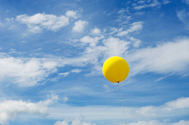 istock Single yellow balloon in a blue sky 491574898