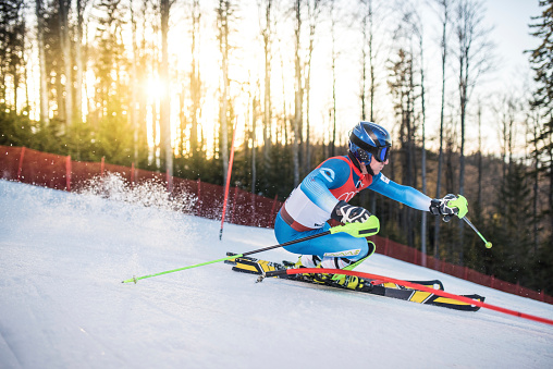 Male ski athlete performing during the FIS Alpine Ski World Cup Competition at sunset. Special simulated FIS World Cup shooting.