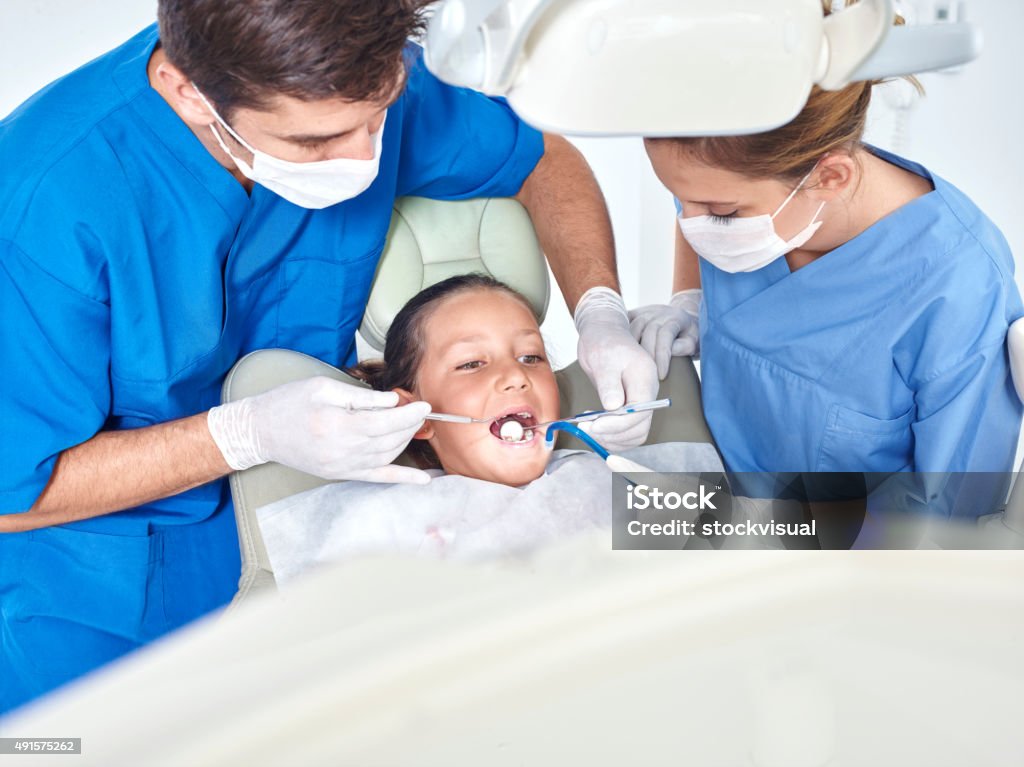 Dentist and assistant examining teeth of little girl Girl and dentists 2015 Stock Photo