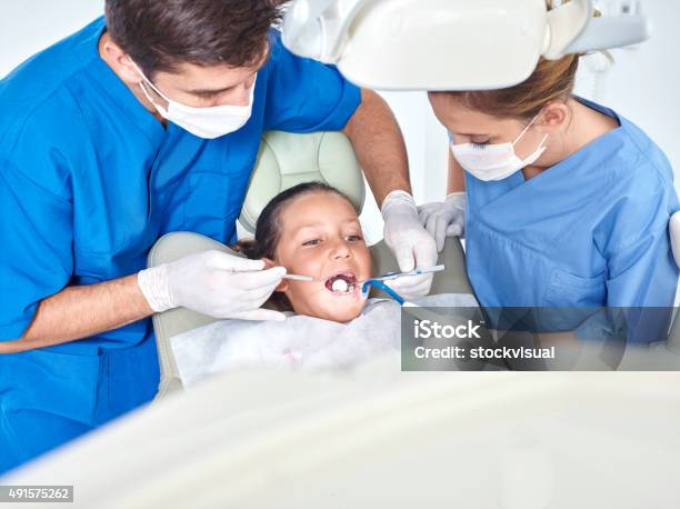 Dentist And Assistant Examining Teeth Of Little Girl Stock Photo - Download Image Now