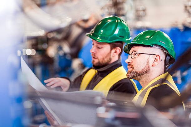istock Colleagues with document in brightly lit factory 491575576