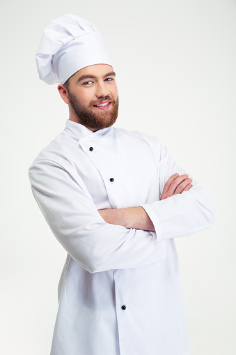 Portrait of a happy male chef cook standing with arms folded isolated on a white background