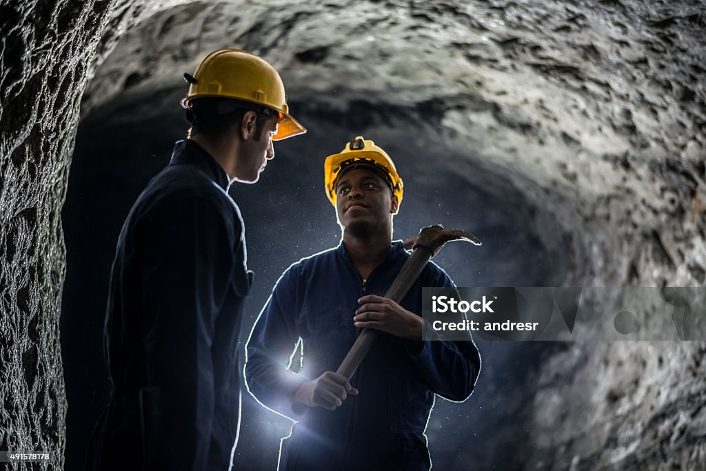Miners working at a mine Miners working at a mine wearing helmets and holding tools - mining concepts Mining - Natural Resources Stock Photo