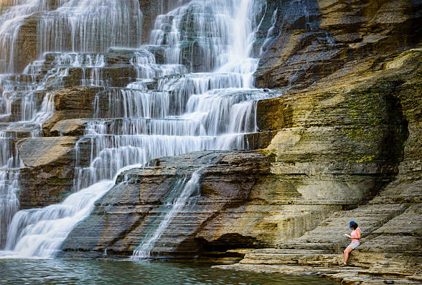 Woman relaxing next to a waterfall,  Ithaca Falls in upstate New York State in the Finger Lakes region.