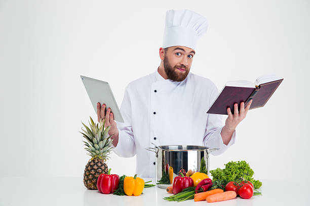 istock Male chef cook holding tablet computer and receipe boo 491581854