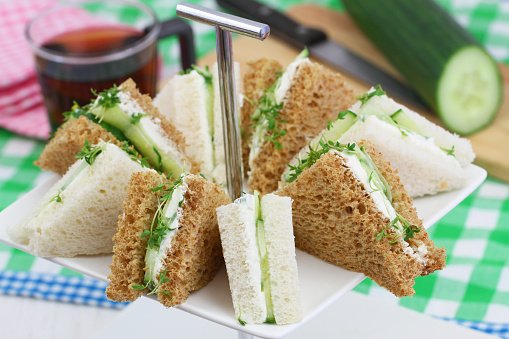 White and brown cream cheese and cucumber sandwiches on cake stand