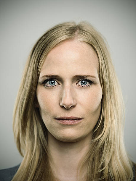 Portrait of a young german woman looking at camera Studio portrait of a german young adult woman looking at camera with relaxed expression. The woman has around 30 years and has long blond hair and blue eyes. Vertical color image from a medium format digital camera. Sharp focus on eyes. blond hair fine art portrait portrait women stock pictures, royalty-free photos & images