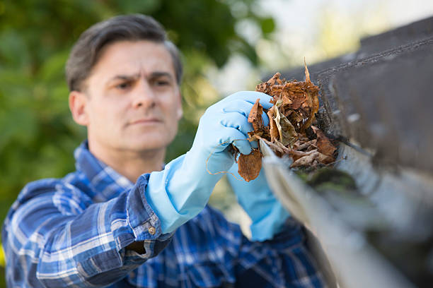 hombre compensación sale de guttering de casa - alero fotografías e imágenes de stock