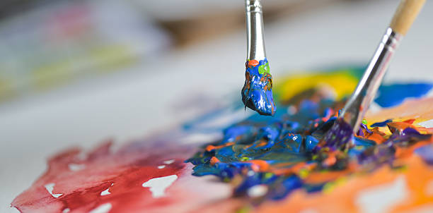 Artist's hand applying paint gouache on the drawing sheet