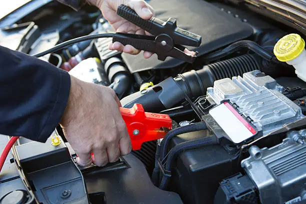 Photo of Close-Up Of Mechanic Attaching Jumper Cables To Car Battery