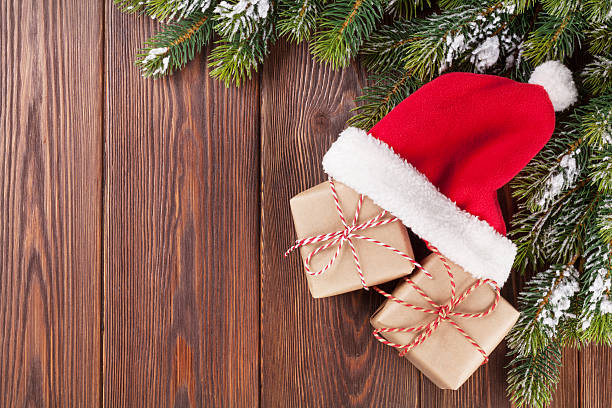 istock Christmas tree branch and santa hat with gifts 491605964